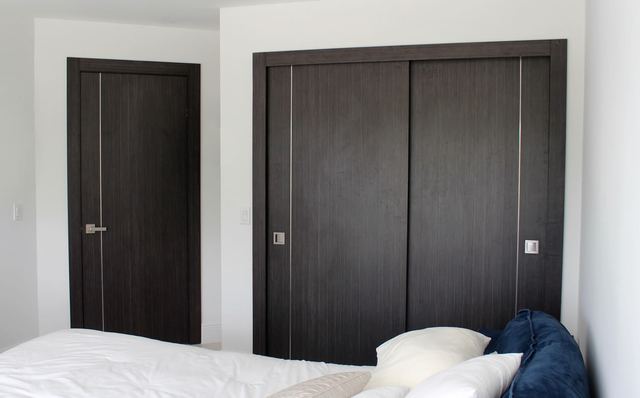 Puertas Mademeco en laminado oscuro con inserto de metal, instaladas en una habitación